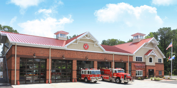 sectional doors opening on a red brick fire bay and fire engines driving through